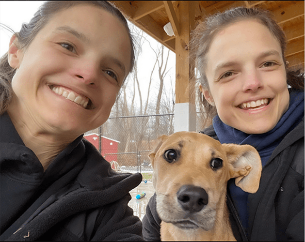 twin sisters volunteering with an adoptable dog